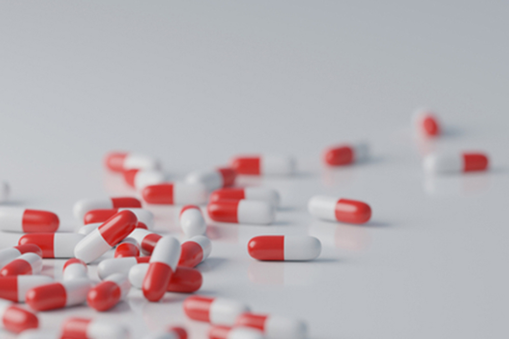 Red and white pills on white background. Pharmaceutical industry, medical treatment, presciption drugs concept. Digital 3D render.