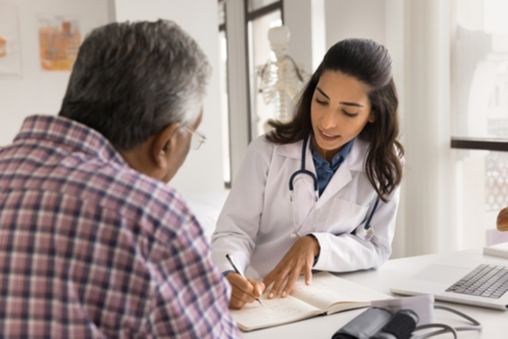 Serious young doctor woman writing down patients complaints, listening to older man visiting practitioner office, giving medical consultation, recommendation for checkup, treatment